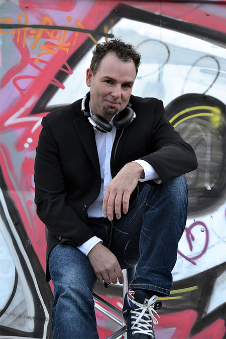 DJ Frank Morris sitzt auf Traverse vor Grafittiwand